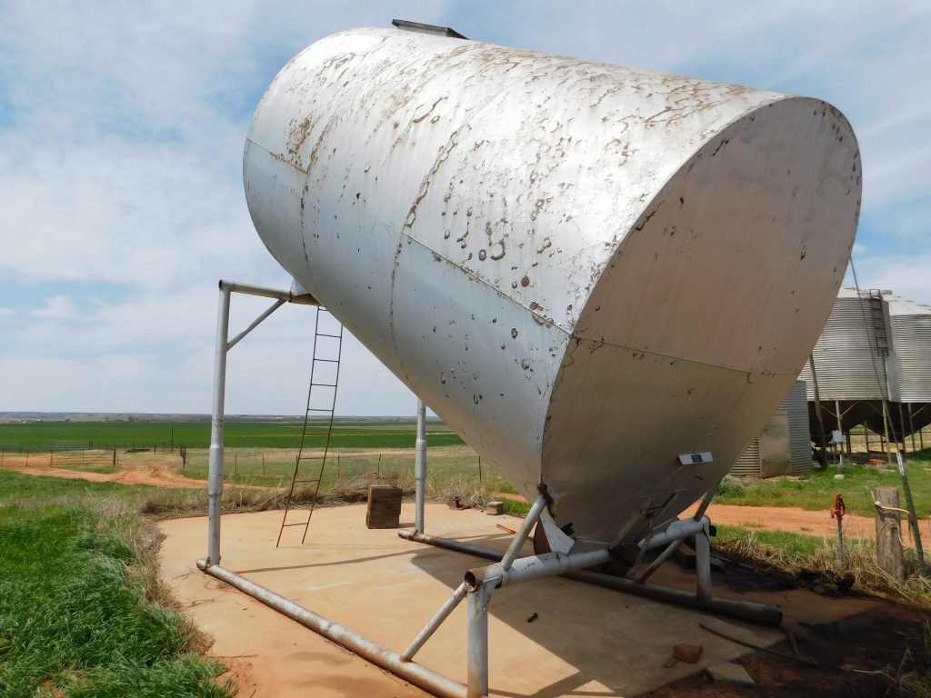 Grain Bin: 210- barrel slant bin made on skid being sold separately from the surface. 10’ wide x 16’ long x 20’ tall